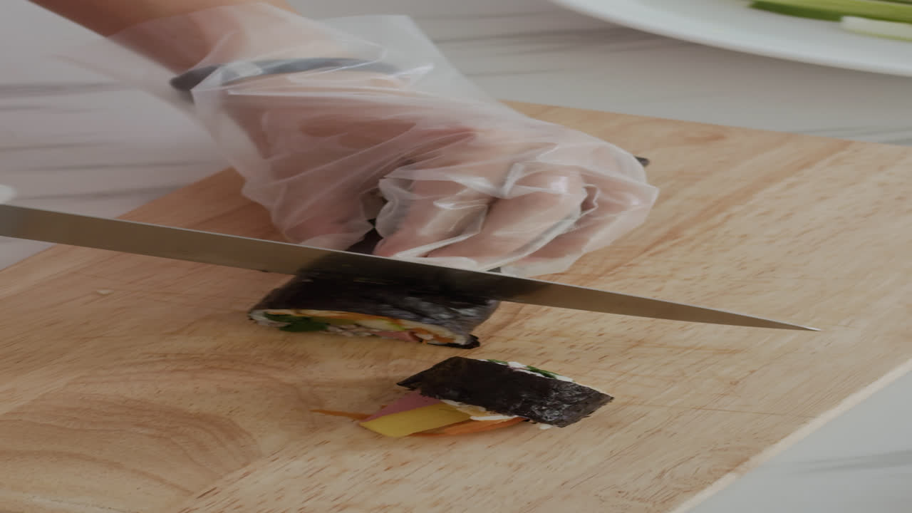 Hands of Woman Cutting Traditional Asian Gimbap