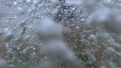 young boy splashing in bubbling spa water moving camera under water to close up on bubbles