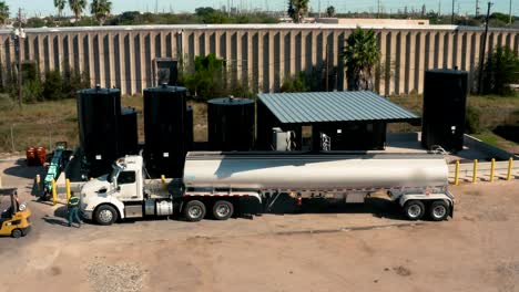 el conductor del camión sale del camión para obtener gas de los grandes barriles de combustible