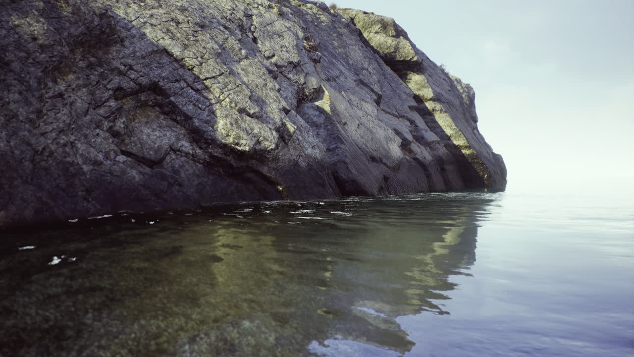 Calm water reflecting rugged rock formations at a tranquil shoreline