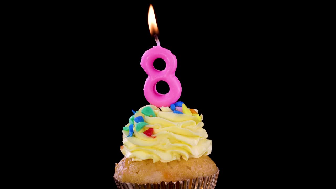 Cupcake singolo con glassa gialla e candelina rosa numero otto accesa su sfondo nero