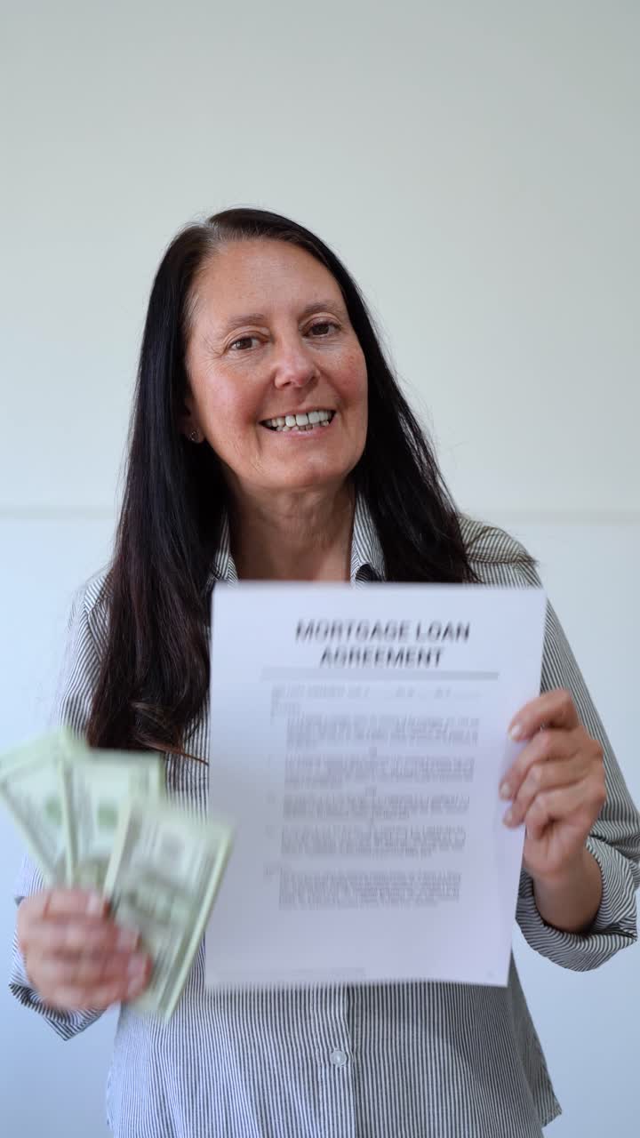 Happy woman holding a mortgage loan agreement and cash. Concept of loan to buy a house. Vertical shot