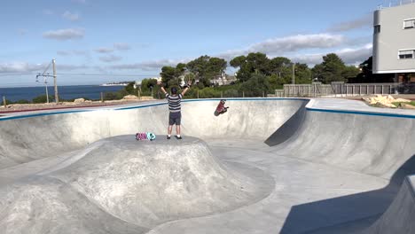 Professional-skater-in-bowl-skatepark-doing-tricks,-skateboarder-carving-a-turn-in-a-deep-concrete-bowl,-young-man-on-extreme-surfboard,-summer-sports