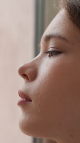 woman looks through window sadly from indoors. attractive lady handles with psychological issues alone at home. frustrated woman overthinks situation