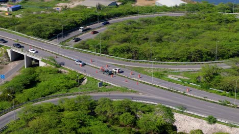 panorámica aérea de gran ángulo de los trabajadores que reemplazan la barrera mediana metálica en la carretera