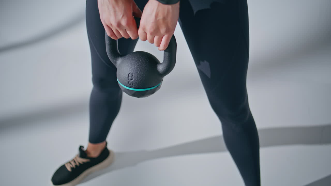 Woman body lifting weight equipment at grey studio. Bodybuilder making squat