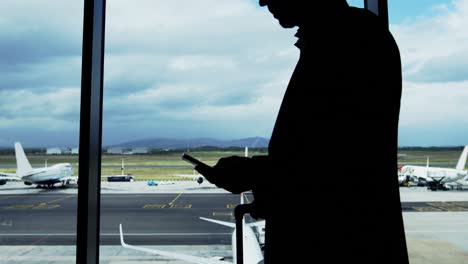 Businessman-texting-on-mobile-phone-at-airport