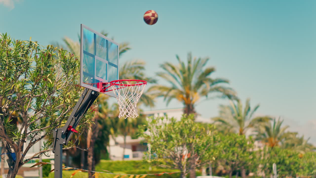 Antibes, France - May 10, 2025: Close up of a basketball missing the hoop with palm trees on the background