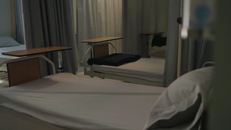 an empty and clean hospital ward featuring multiple beds, curtains, and bedside tables.