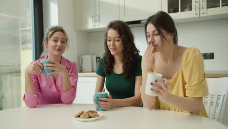 friends gossiping together with coffee and cakes at the kitchen, slow motion