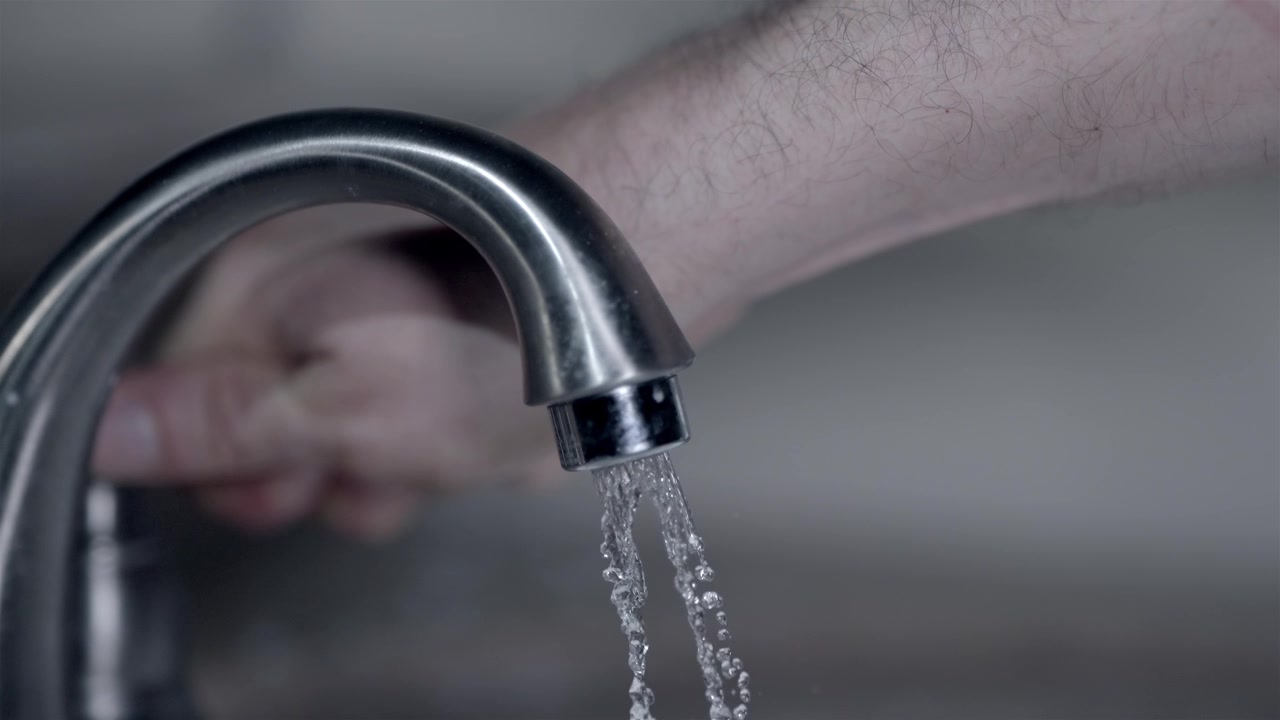 Close up of person gradually turning on the water from a metal faucet
