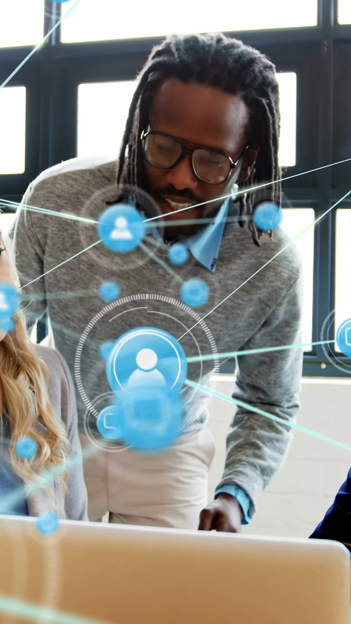 Vertical video: Man leaning in and pointing at laptop, team watching network icons pulsing for tech