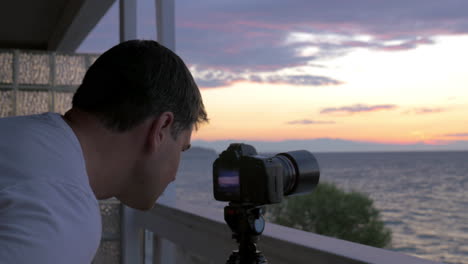 Hombre-Disparando-Timelapse-De-La-Puesta-De-Sol-Sobre-El-Mar