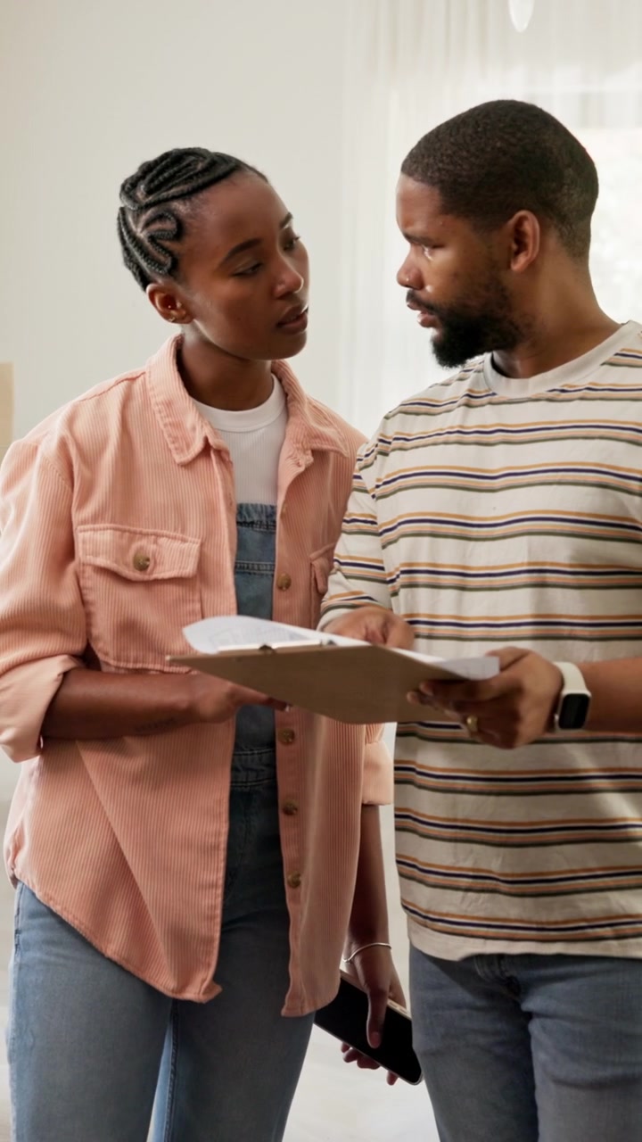 Young Couple Reviewing Documents on Clipboard in New Home