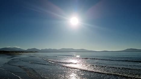 slow motion tide waves splashing under calming hazy sunrise snowdonia mountain range skyline