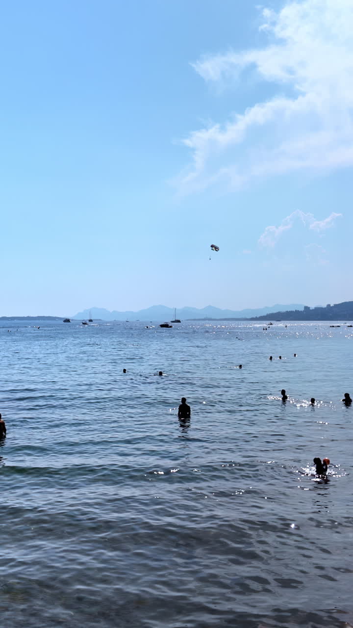 People swimming in the sea and relaxing on the beach in Juan-les-Pins, France. Vertical