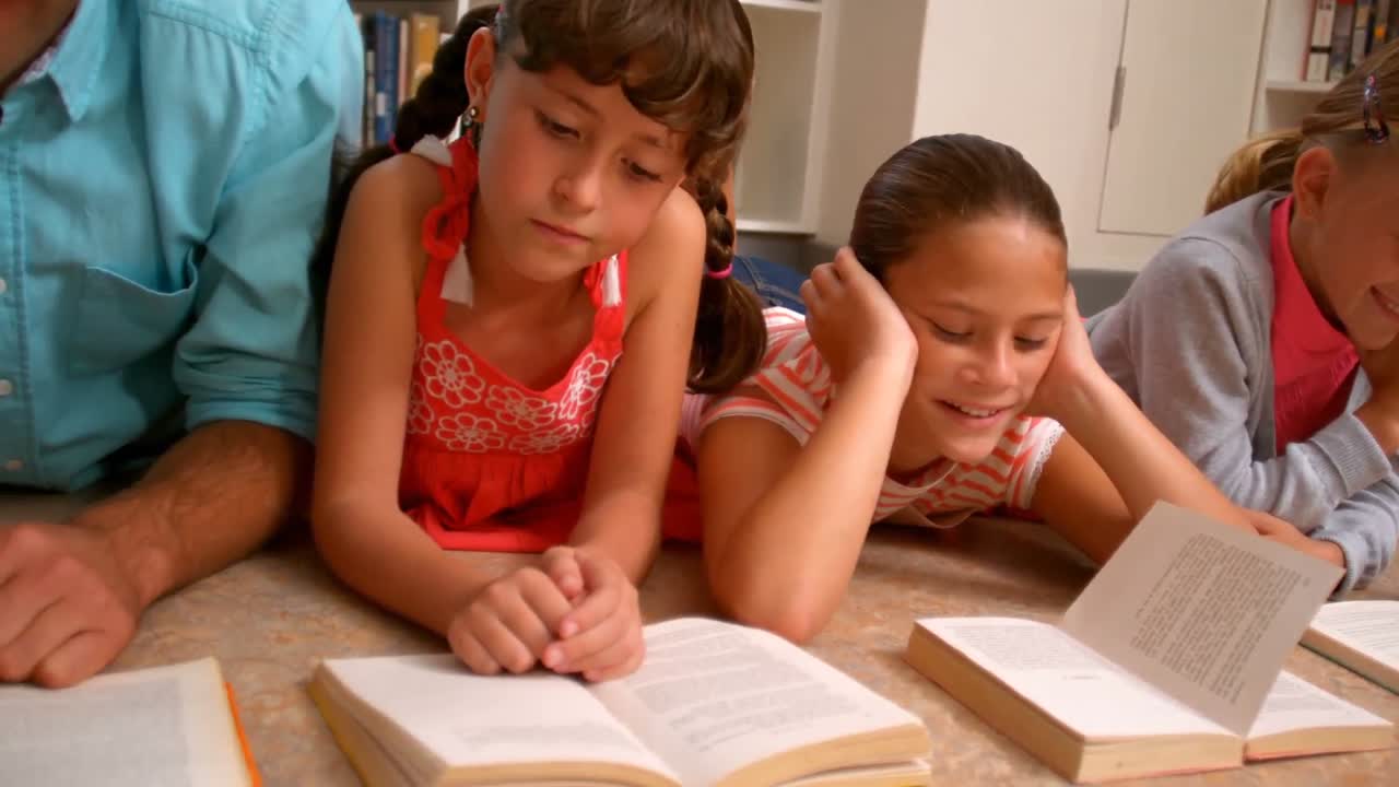 Profesor y niños leyendo el libro en la biblioteca