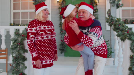 happy girl granddaughter meeting her lovely grandparents, embracing, hugging at xmas christmas home