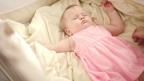hermoso bebé durmiendo en la cuna. las manos de la madre acariciando al niño durmiendo