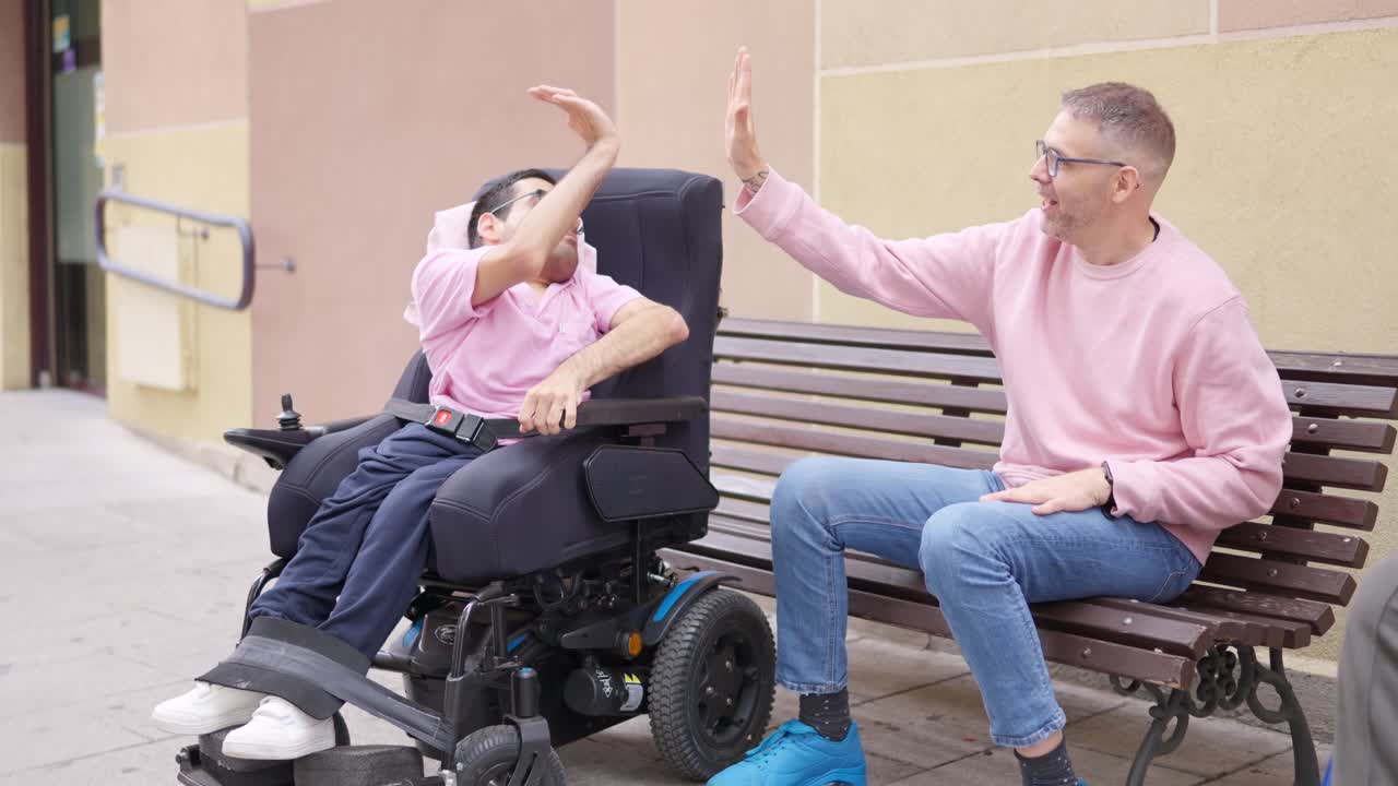 Happy Men Giving High Five, One in Wheelchair, Outdoors