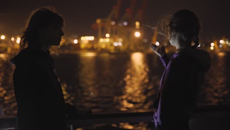 silhouette of two attractive young women traveling on a ship at night. girlfriends on the boat