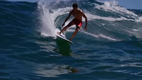 Dynamic video still of a surfer riding a wave, captured from a low side angle