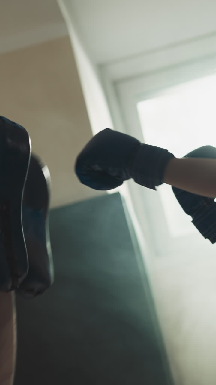 Instruktur melatih anak kecil meninju di gym. Pelatih ramah menyesuaikan kepalan tangan gadis ke posisi yang tepat untuk tinju di klub olahraga dalam gerak lambat. Aktivitas fisik.
