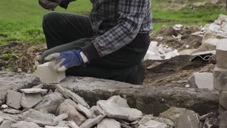 construction worker removing old cement from bricks, close up view