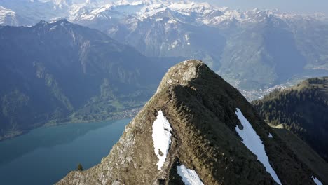 hombre caminando en la cima de una hermosa cresta entre enormes montañas y por encima de un valle verde con un lago azul
