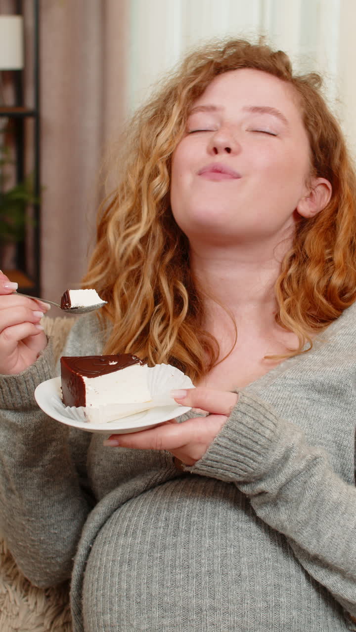 Pregnant woman eating cake at home smiling with satisfaction enjoying sweet taste and happy moment