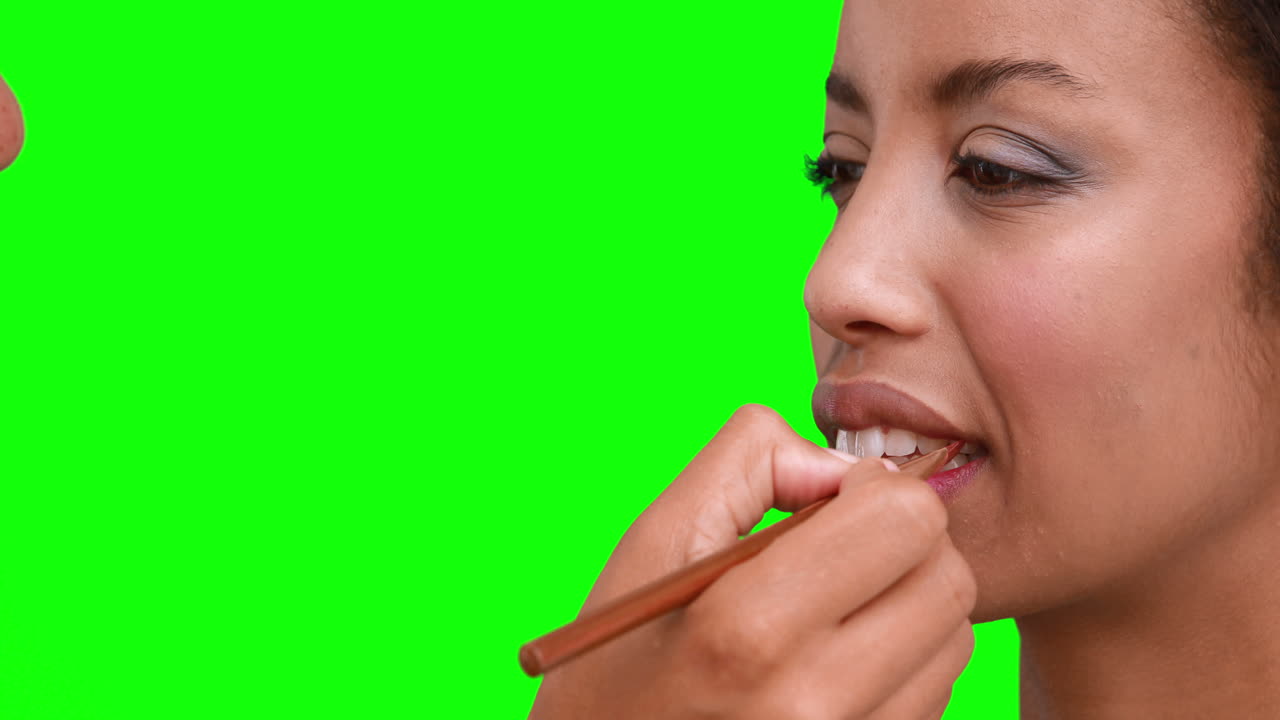 Truccatrice che applica il lucidalabbra sul viso della modella