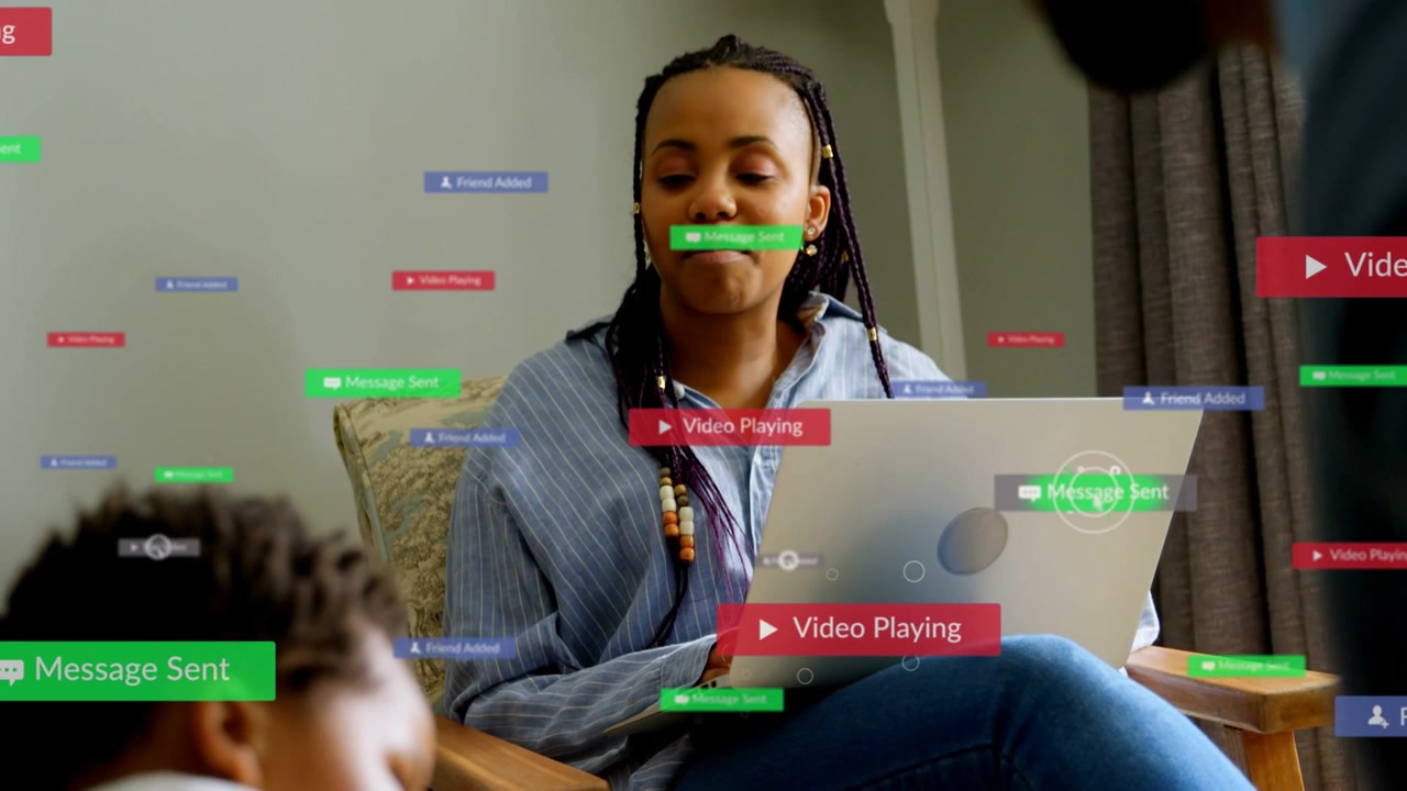 Mother tapping laptop at home, animated UI labels growing over family, speaking and sharing media