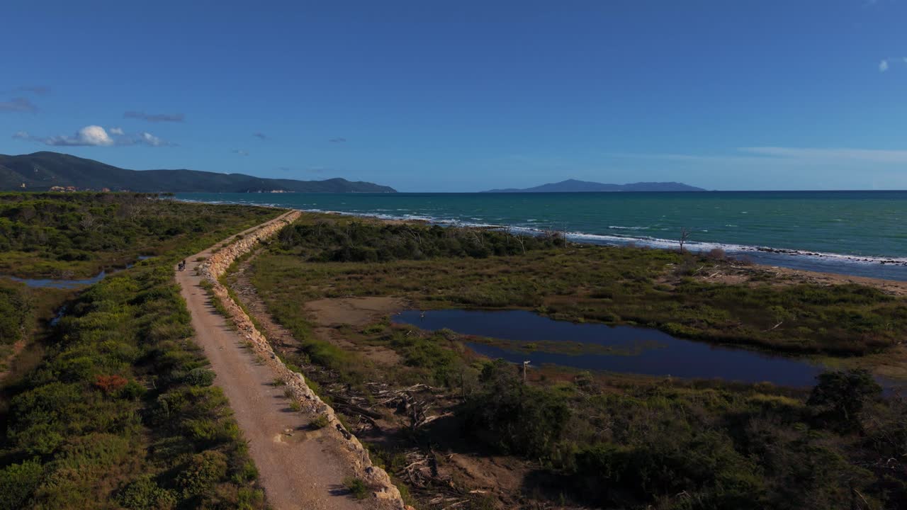 Aerial of Parco Maremma coastline with soft dunes, beach, seaside and green forest. Tuscany