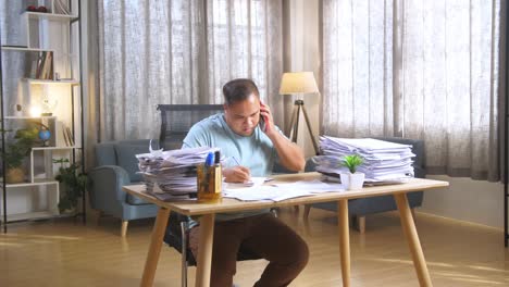 hombre trabajando desde casa, abrumado por papeles