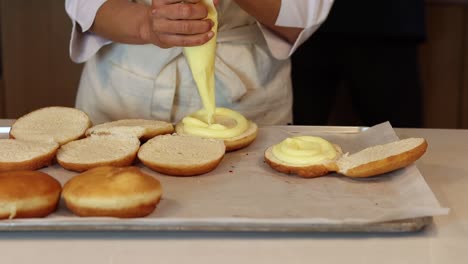 Cocinero-De-Cultivos-Decorando-Berlineses-Con-Crema-En-La-Cocina