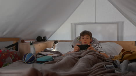 boy playing games on his smartphone in bed