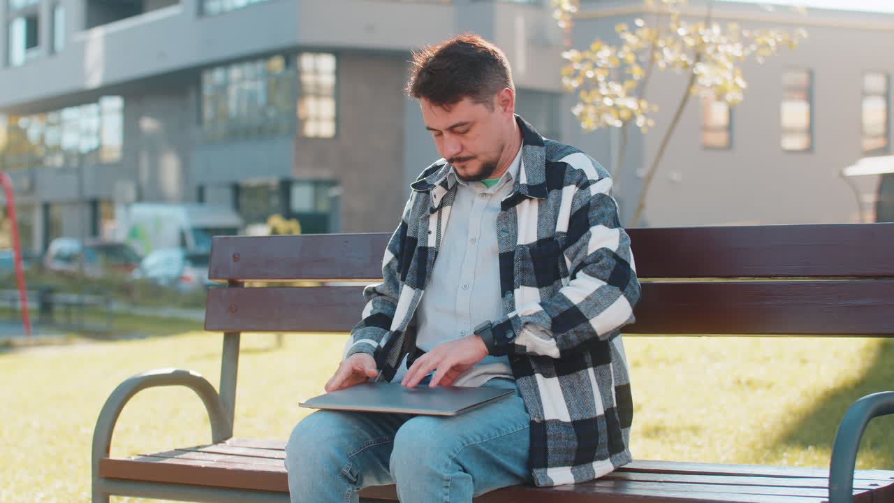 hombre caucásico maduro freelance trabajando en línea trabajo remoto usando portátil sentado en un banco en la ciudad