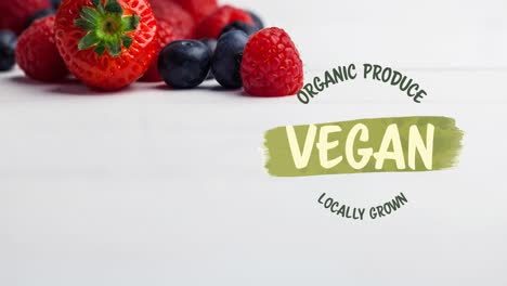 Animation-of-vegan-text-in-green-over-fresh-organic-berries-on-white-background