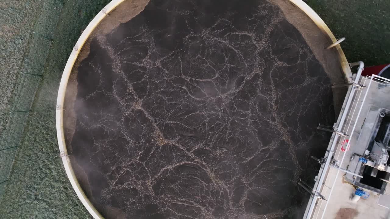 Drone footage of circular wastewater treatment tank with aeration, symbolizing purification and environmental care, industrial setting, brown water