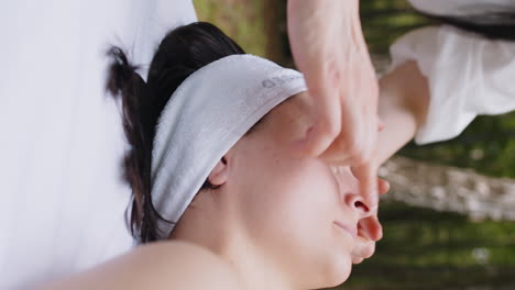 therapist female doctor making woman relaxing spa face massage with hands outdoors in the forest