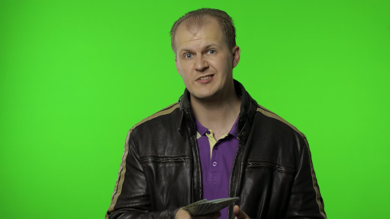 rocker hombre empleado tomar dinero dólar billetes en efectivo de su bolsillo y los ofrece a la cámara