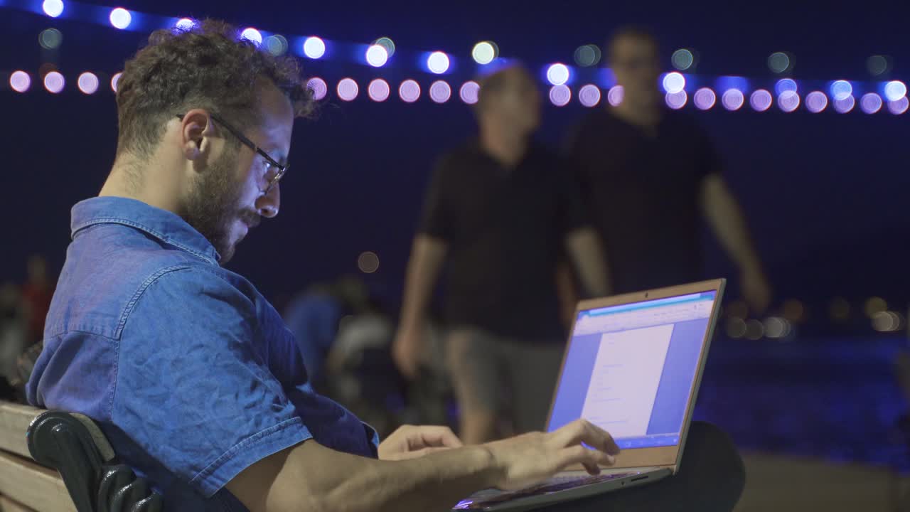 hombre de negocios trabajando en su portátil al aire libre. playa por la noche.