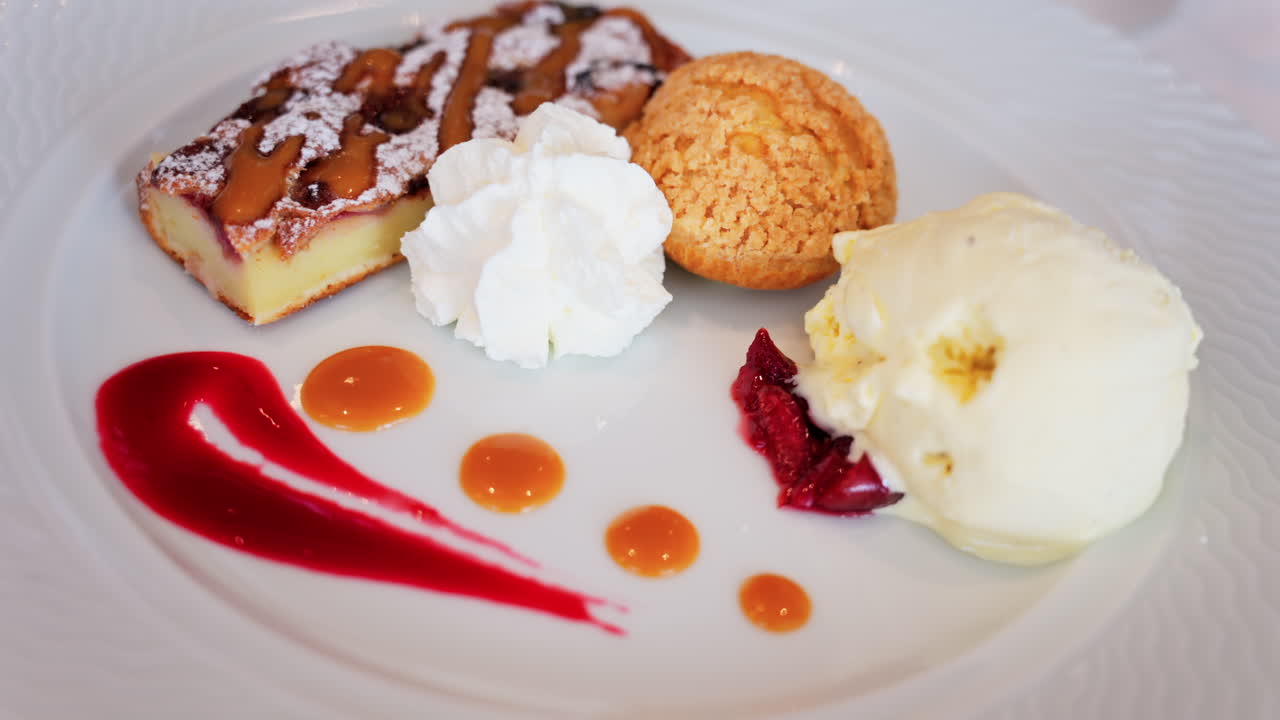 Close up of a dessert plate with a tart, a cream puff, ice cream, and sauces