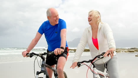 front view of old caucasian couple riding bicycle at beach 4k