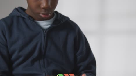 studio shot of boy on asd spectrum solving puzzle cube wearing ear defenders 2