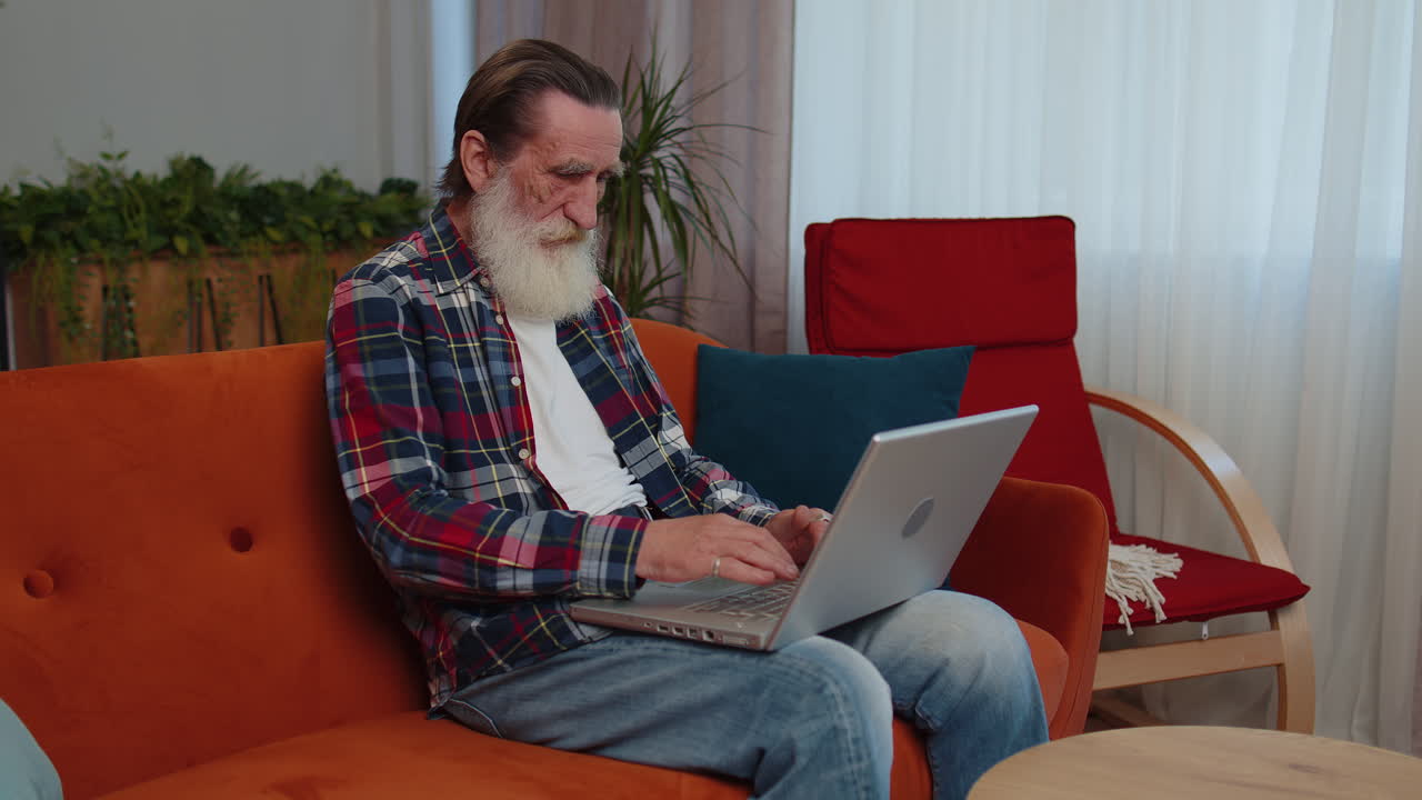 abuelo mayor hombre independiente trabajando en portátil, envía mensajes, hace compras en línea en casa