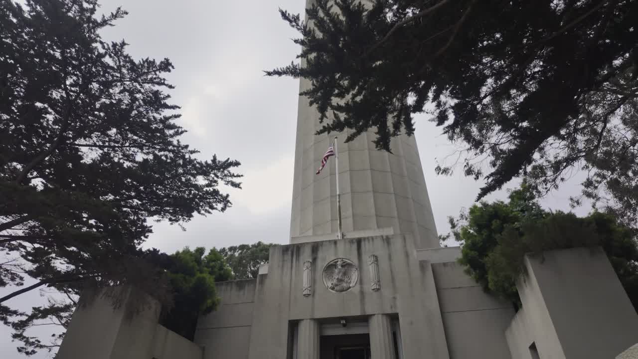 Visualizzazione della Coit Tower dietro gli alberi con la bandiera americana che sventola