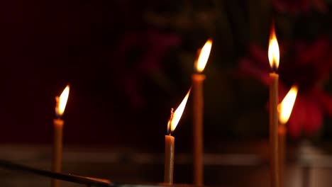 religious altar with a crucifix framed in gold against a red backdrop, surrounded by lit candles and a colorful bouquet of fresh flowers