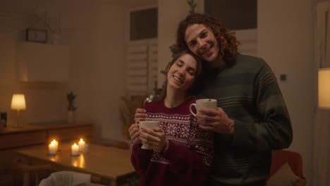 couple enjoying hot drinks by the christmas tree