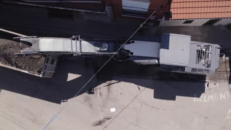 aerial birds eye view of road milling machine removing old asphalt and loads milled asphalt into the dump truck in navas del rey street in spain